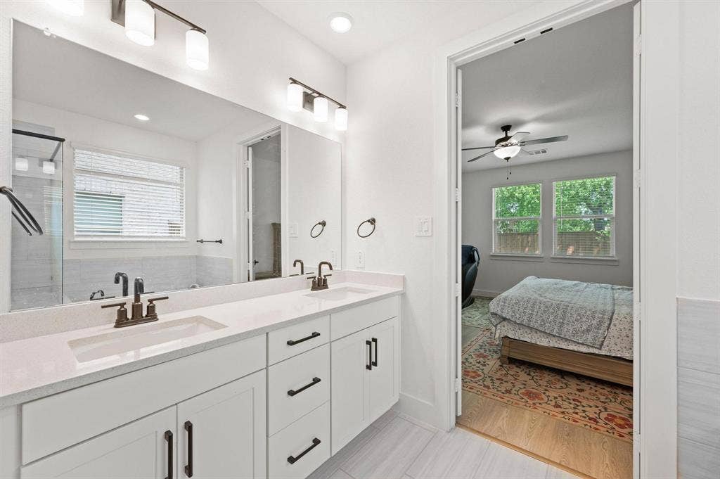Dual vanities with integrated sinks, white cabinetry, and bronze-finish hardware