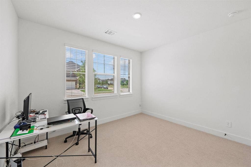 Carpeted flooring, white walls, multiple windows with blinds, and recessed lighting