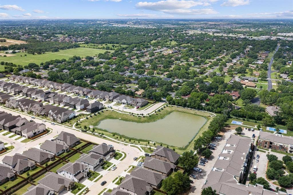 Expansive residential development featuring a large central pond, multiple community swimming pools, and a mix of single-family homes and multi-story apartment buildings