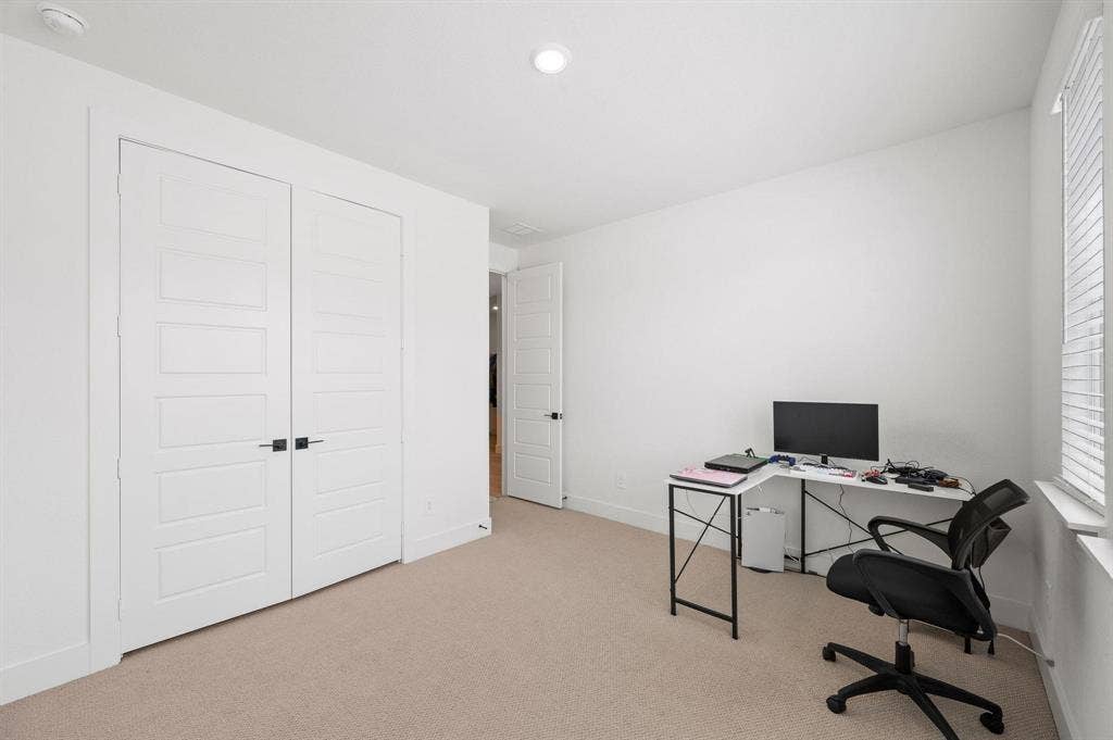 Neutral-toned carpeting, white walls, and a window with blinds