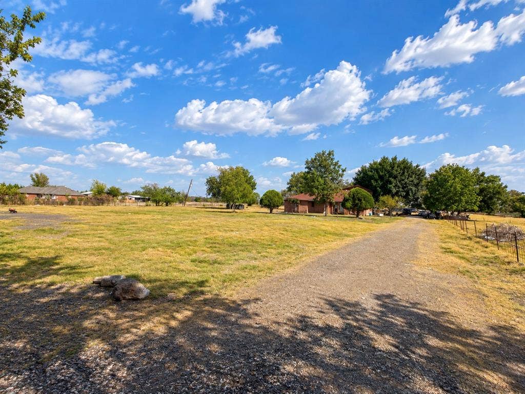 2429 Neck Road, Palmer, TX 75152 Expansive outdoor grounds featuring a gravel drive, mature trees, and a wire fence