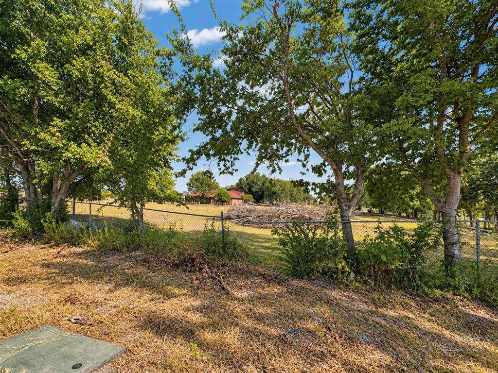 2429 Neck Road, Palmer, TX 75152 Expansive property featuring mature trees and a chain-link fence