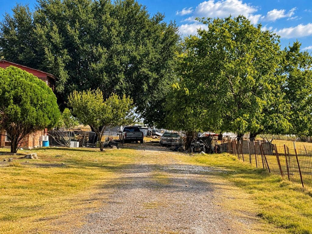 2429 Neck Road, Palmer, TX 75152 Gravel driveway with mature trees and a brick exterior