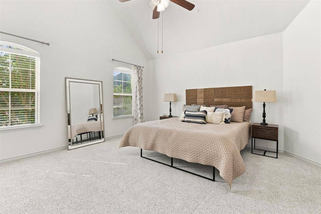 5605 Cojimar Drive, McKinney, TX 75070 Vaulted ceiling with a ceiling fan, two arched windows with blinds, and light-colored carpeting