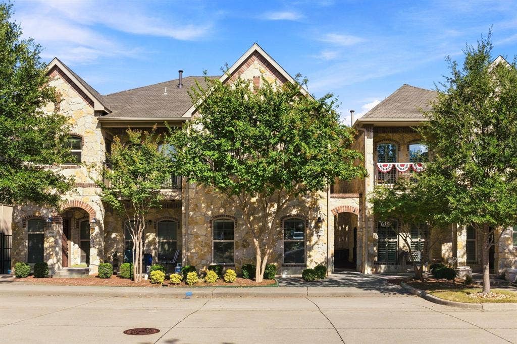 5605 Cojimar Drive, McKinney, TX 75070 Stone facade exterior with arched entryway, second-story balcony, and mature trees