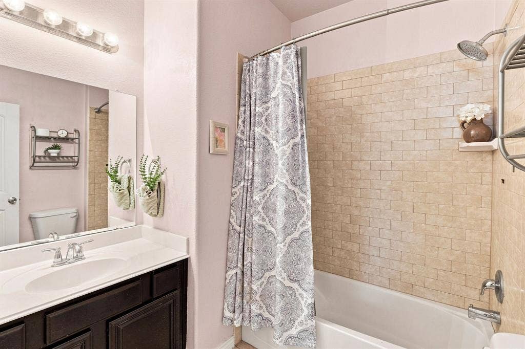 5605 Cojimar Drive, McKinney, TX 75070 Built-in bathtub with subway tile surround, chrome showerhead, and wall-mounted shelving