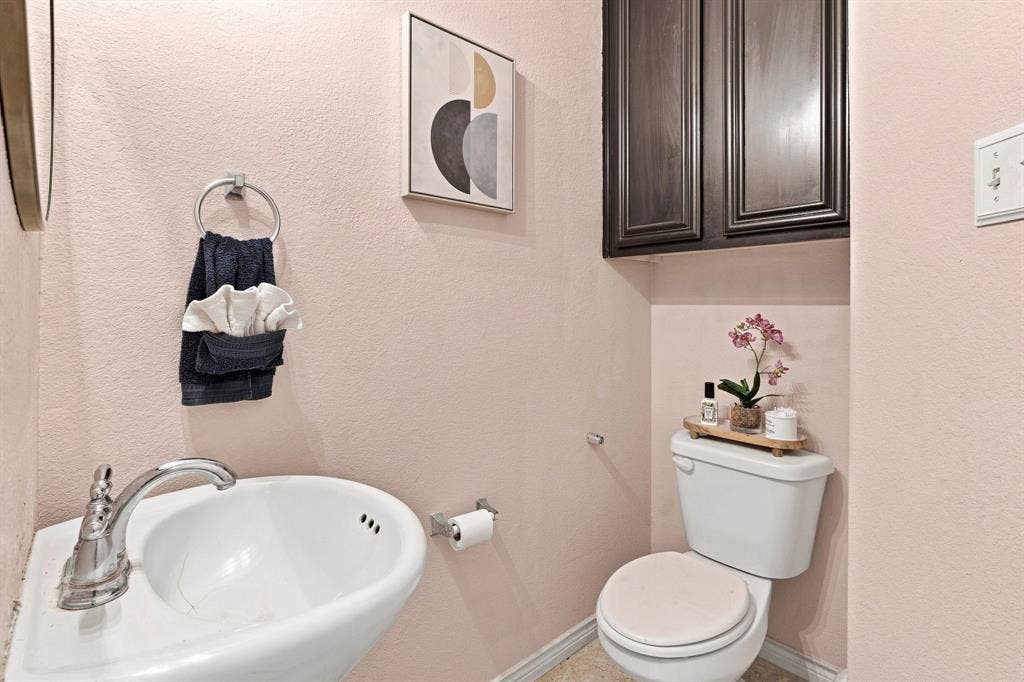 5605 Cojimar Drive, McKinney, TX 75070 Pedestal sink with chrome-finish faucet, toilet, and dark wood-finish cabinetry