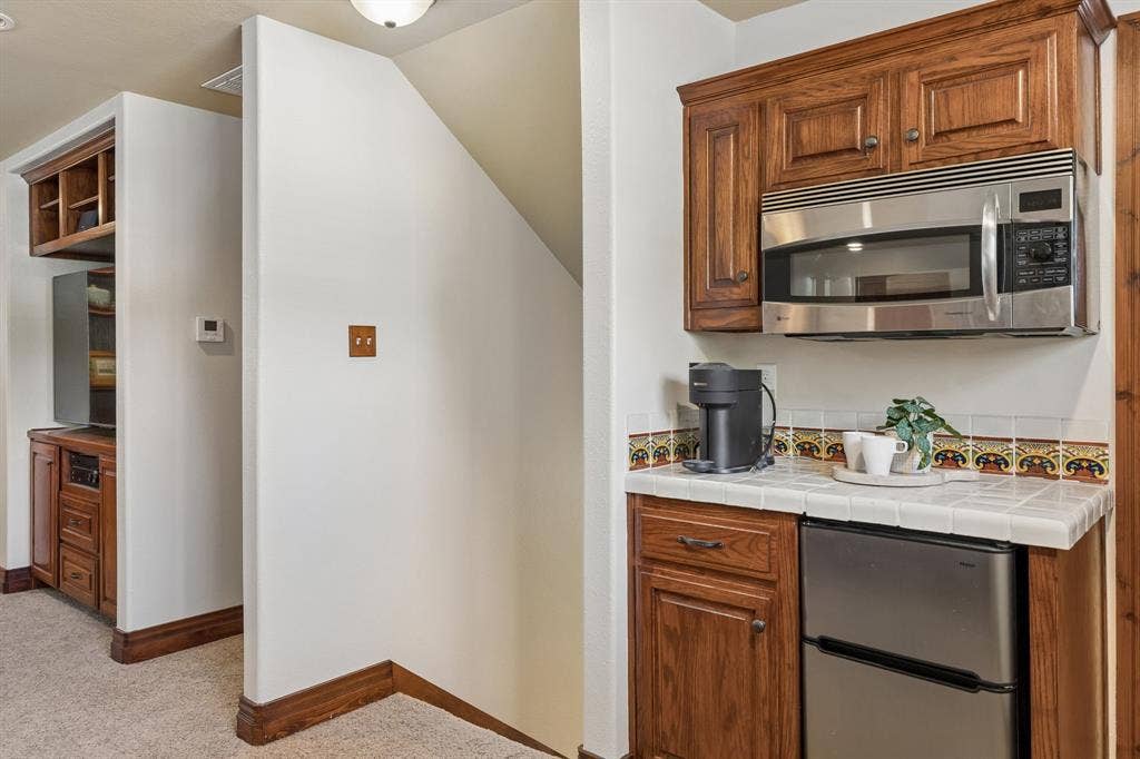 3227 Berry Hollow, Melissa, TX 75454 Built-in cabinetry with wood-finish, stainless steel microwave, tile countertop, and compact refrigerator