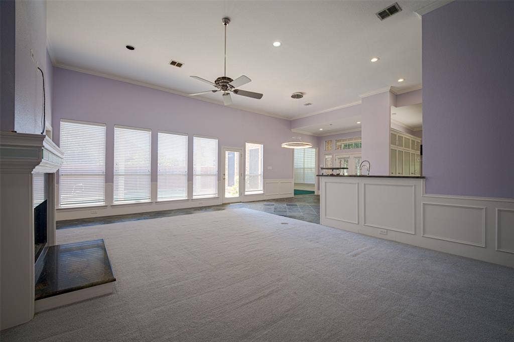 Vaulted ceiling with recessed lighting and a ceiling fan, fireplace with a dark stone hearth, a wall of windows, and a built-in bar with a dark countertop and sink