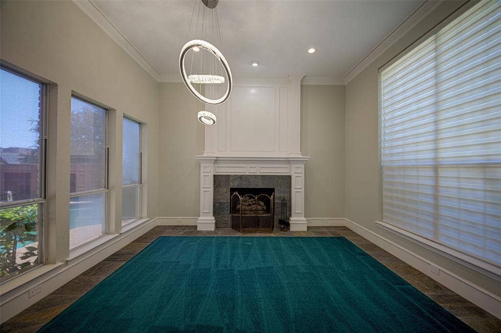 White mantel fireplace with stone surround, complemented by a modern multi-ring chandelier