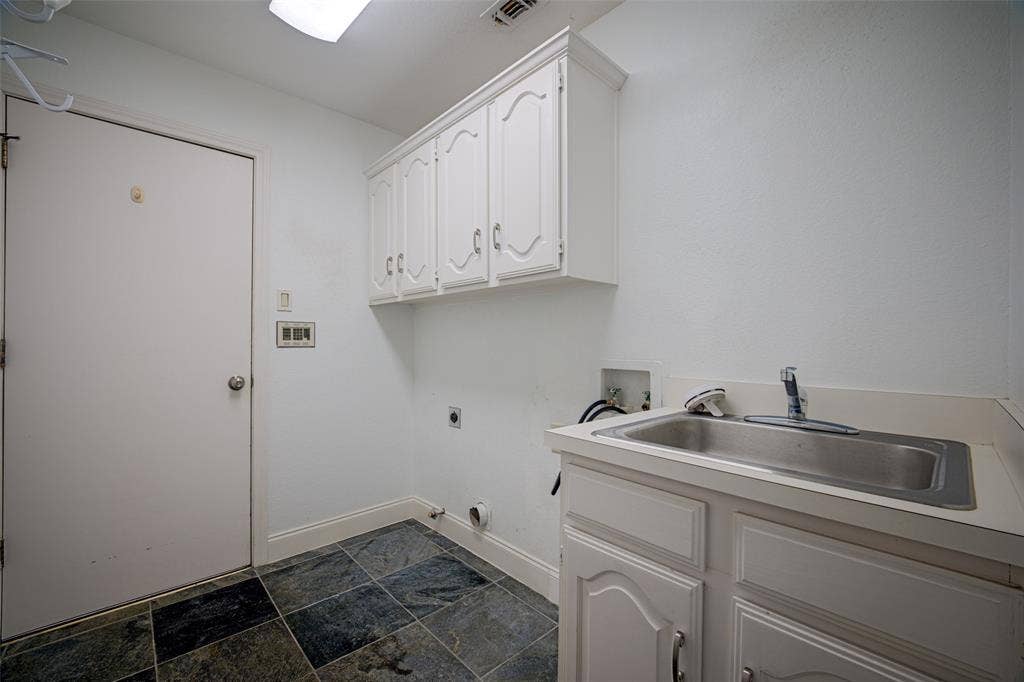 Laundry area with a utility sink, white cabinetry, and multi-toned tile flooring
