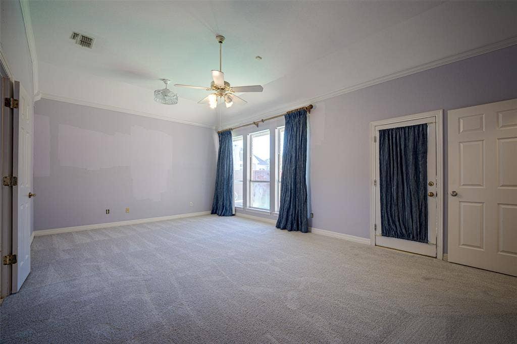 Primary bedroom with crown molding, two ceiling fans, and a carpeted floor