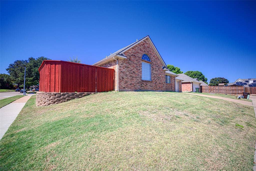 Brick exterior featuring an arched window, attached garage, and a wood privacy fence