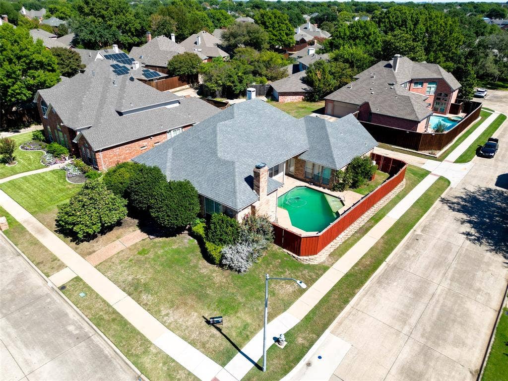 Red brick exterior with a gray shingle roof, featuring a private swimming pool and an exterior privacy fence