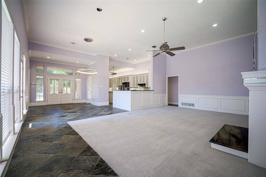 Vaulted ceiling, recessed lighting, ceiling fan, fireplace with stone hearth, and white wainscoting