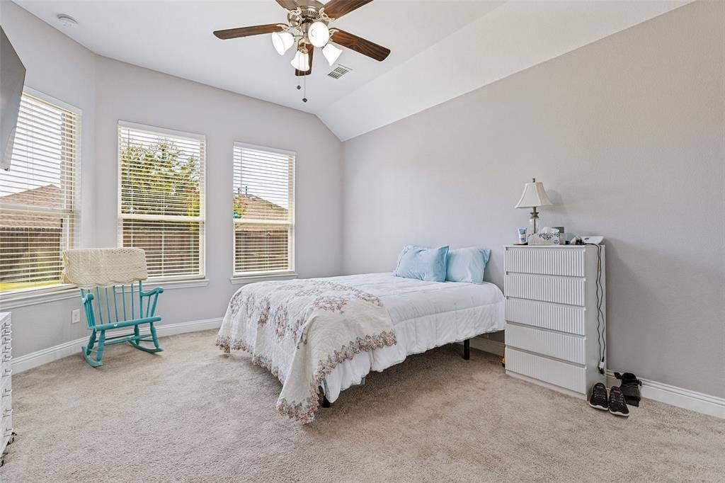 1004 Baynes Drive, McKinney, TX 75071 Vaulted ceiling with a ceiling fan, three windows with blinds, and light-toned carpeting