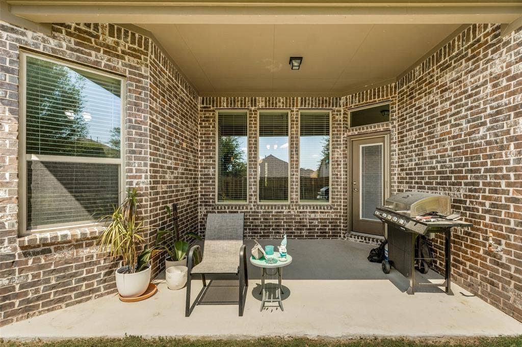 1004 Baynes Drive, McKinney, TX 75071 Covered patio with brick exterior, concrete flooring, and multiple windows
