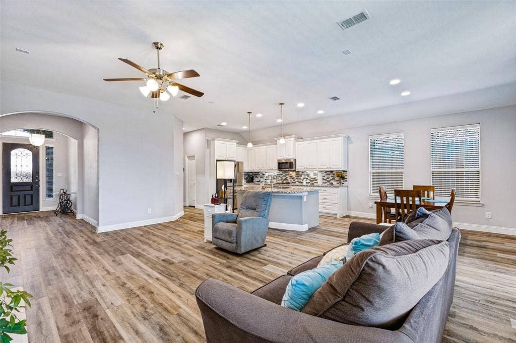 1004 Baynes Drive, McKinney, TX 75071 Wood-finish flooring throughout, recessed lighting, ceiling fan, white kitchen cabinetry, and a dark paneled front door