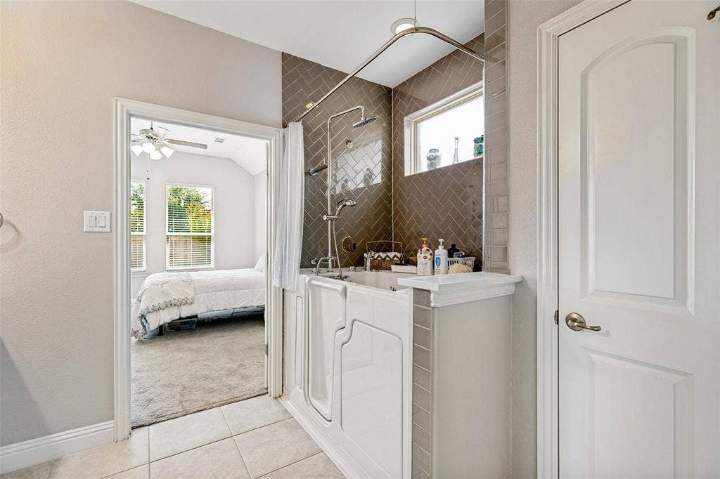 1004 Baynes Drive, McKinney, TX 75071 Walk-in tub with a herringbone tile surround, window, and integrated shower system
