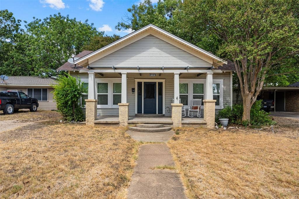 302 W Broadway Street, West, TX 76691 Gable roofline, covered front porch with column supports, and a dark-paneled front door