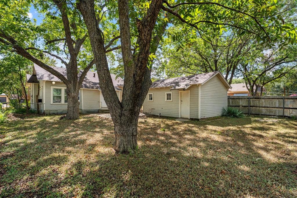 302 W Broadway Street, West, TX 76691 Expansive backyard featuring mature trees, a detached auxiliary building, and a wood privacy fence