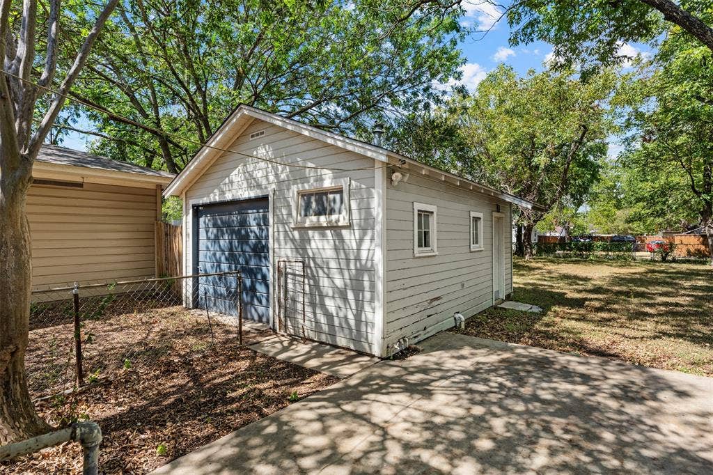 302 W Broadway Street, West, TX 76691 Detached garage with horizontal siding, a blue overhead door, and multiple windows