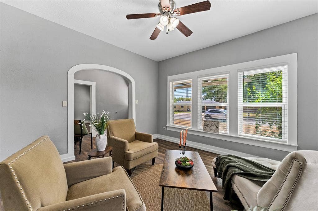 302 W Broadway Street, West, TX 76691 Bright living area featuring wood-finish flooring, a ceiling fan with light fixture, and a three-panel window with white trim