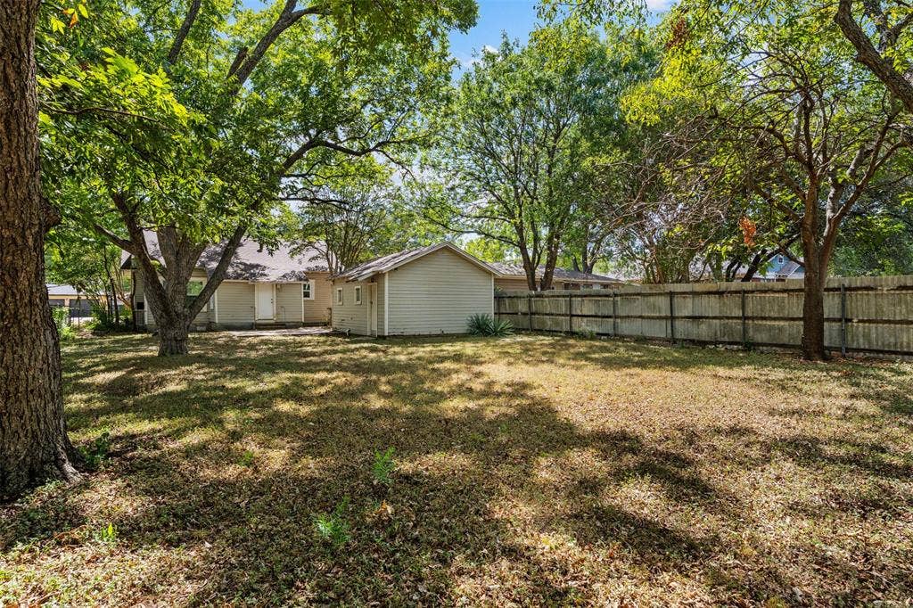 302 W Broadway Street, West, TX 76691 Expansive backyard featuring mature trees, a detached storage building, and a wood privacy fence