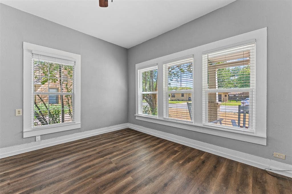 302 W Broadway Street, West, TX 76691 Wood-finish flooring, light gray wall paint, and multiple windows with white blinds