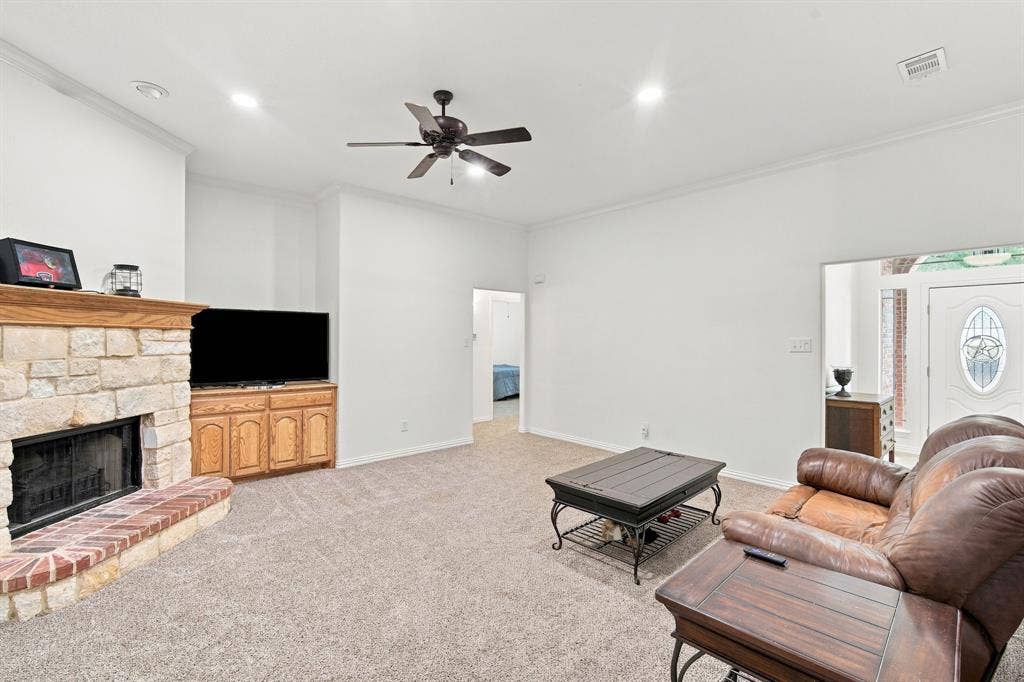 Inviting living space featuring a stone fireplace, brick hearth, and custom wood-finish built-in cabinetry.