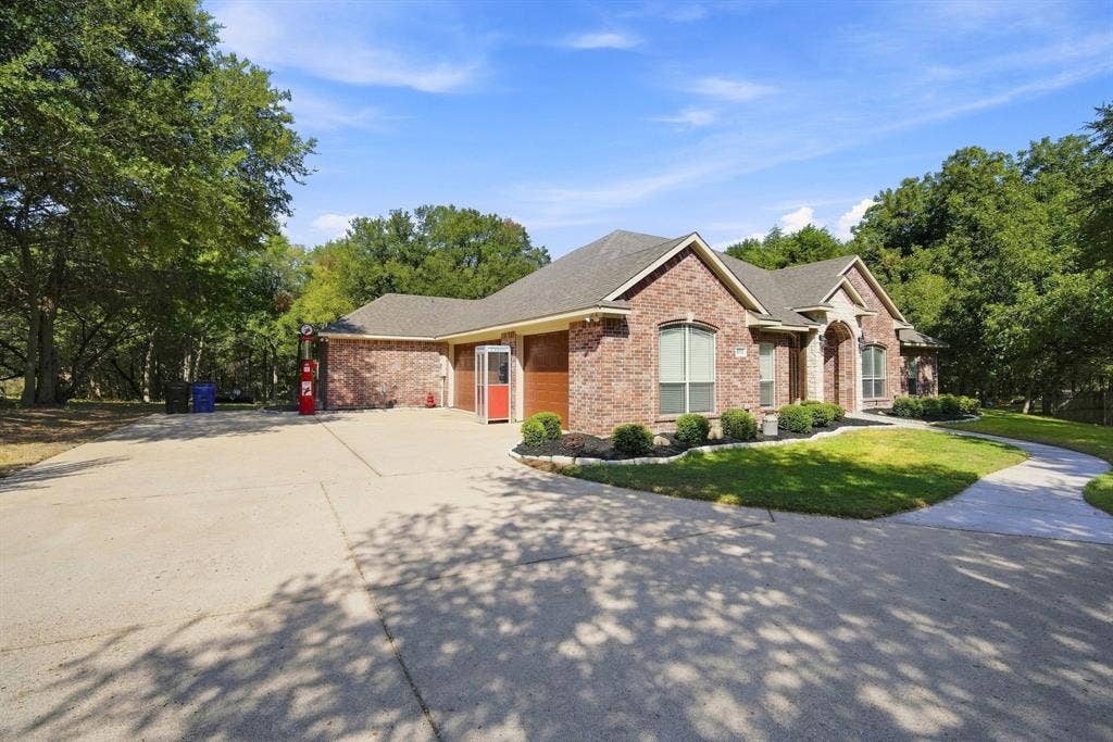 Mature shade trees and a wide concrete driveway lead to this beautifully landscaped brick and stone home.