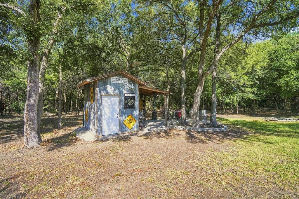 Tucked beneath the trees, this rustic outbuilding adds charm and versatility to your backyard oasis.