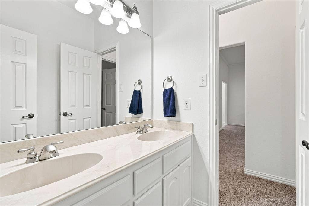 Well-appointed bathroom with dual undermount sinks, brushed nickel fixtures, and a spacious vanity mirror.