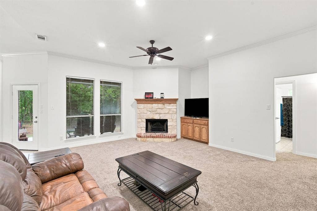 Cozy living room anchored by a striking stone fireplace with a brick hearth and warm wood mantel.