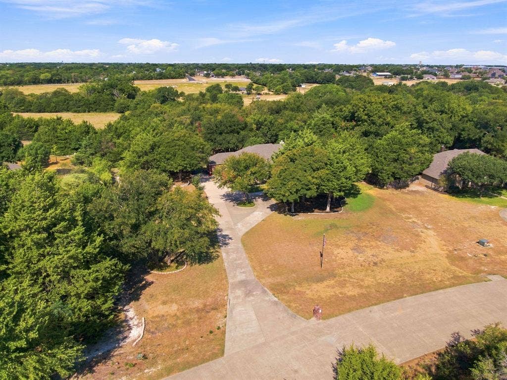 Aerial perspective highlighting the sprawling, tree-lined acreage that surrounds this private property.