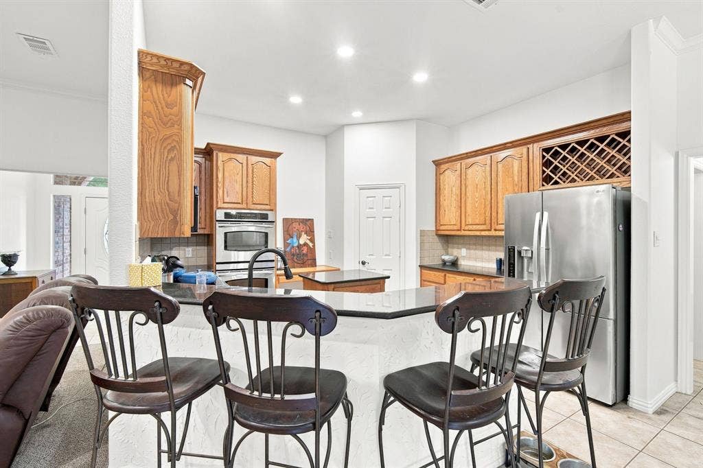 Chef-ready kitchen boasting rich wood cabinetry, a built-in wine rack, and a spacious island with breakfast bar seating.