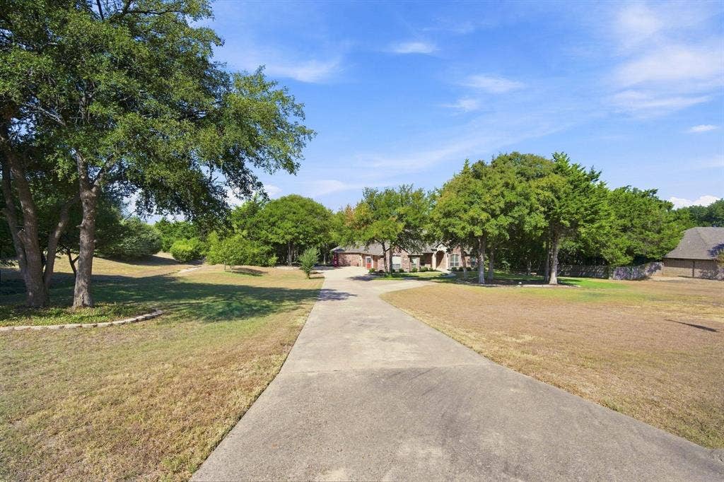 Long paved driveway winds through the property, framed by open green space.