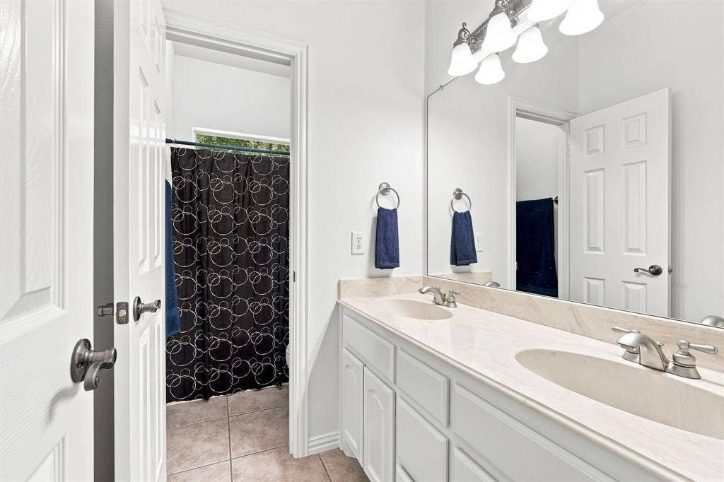 Elegant bathroom featuring a dual vanity, brushed nickel fixtures, and a polished stone countertop.