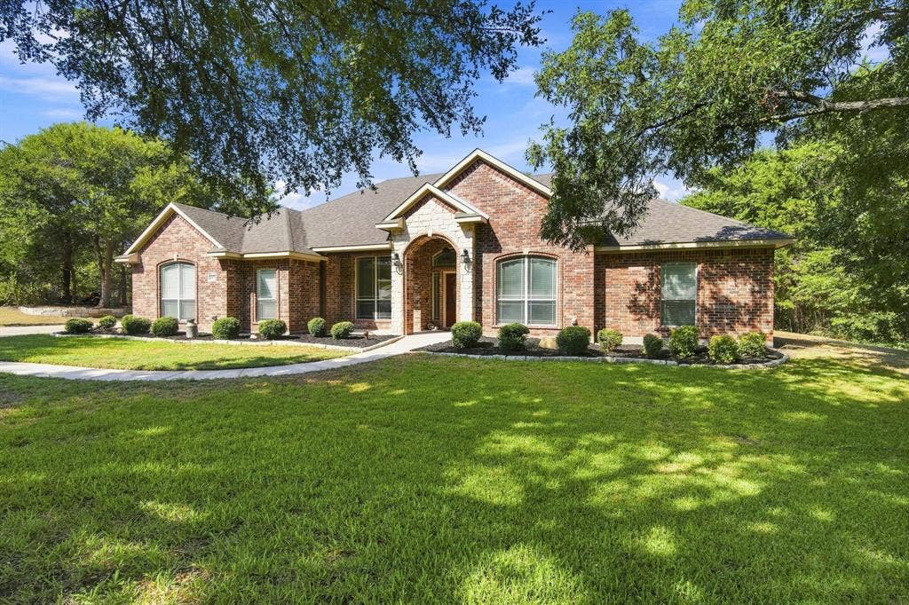 Handsome brick and stone facade with an arched entry, tall windows, and a beautifully landscaped walkway welcoming you home.
