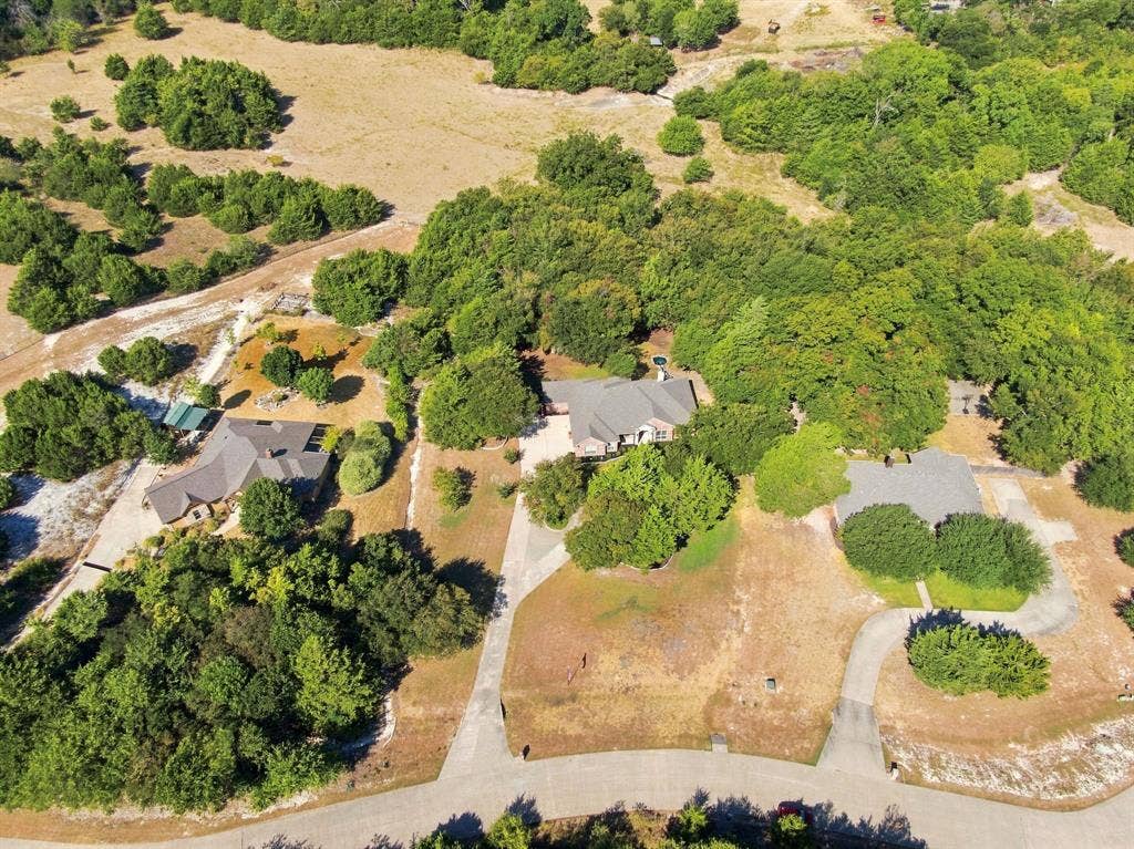 Aerial view showcasing the full property, including three distinct residences, mature trees, and paved driveways.
