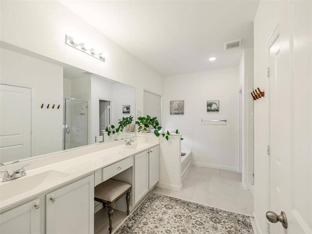Dual vanity with integrated sinks, expansive counter space, recessed lighting, tile flooring, and built-in tub