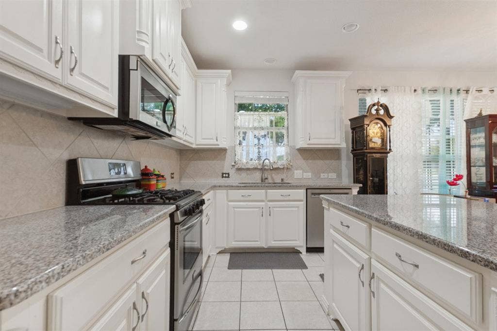 524 S Greenville Avenue, Richardson, TX 75081 The roomy kitchen boasts white cabinetry, granite countertops, tile flooring, stainless steel appliances, and a tile backsplash!
