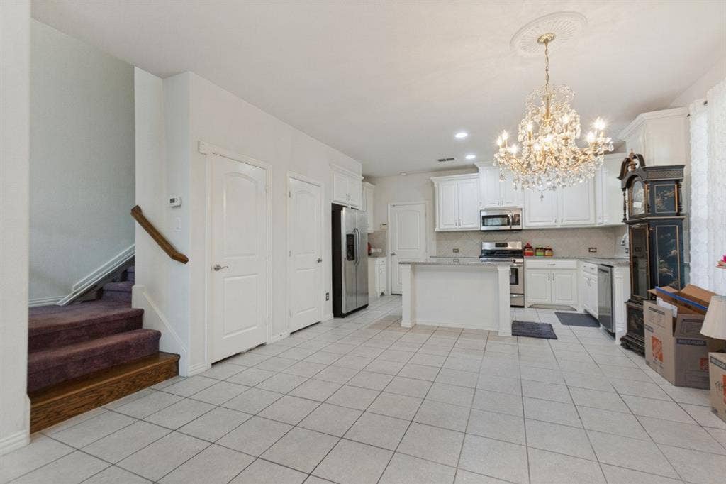 524 S Greenville Avenue, Richardson, TX 75081 Spacious kitchen featuring elegant white cabinetry, modern stainless steel appliances, a functional center island with stone countertops, and durable tile flooring.