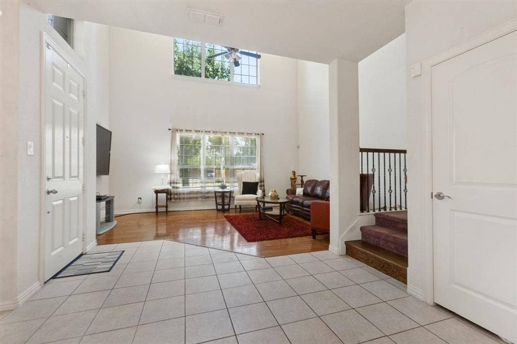 524 S Greenville Avenue, Richardson, TX 75081 Vaulted ceilings, large windows, wood-finish flooring, tiled entry, and a staircase with wrought iron balusters