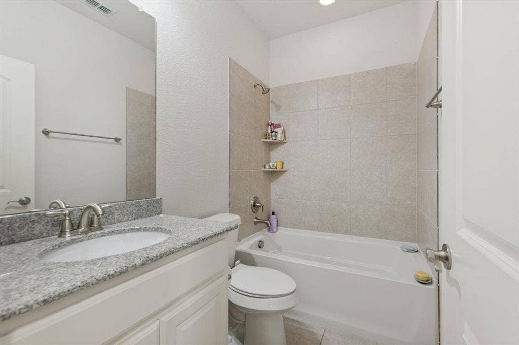 524 S Greenville Avenue, Richardson, TX 75081 This guest bathroom features a bright, clean design highlighted by a crisp white vanity cabinet topped with elegant, durable granite countertops, offering a modern and inviting aesthetic for visitors.