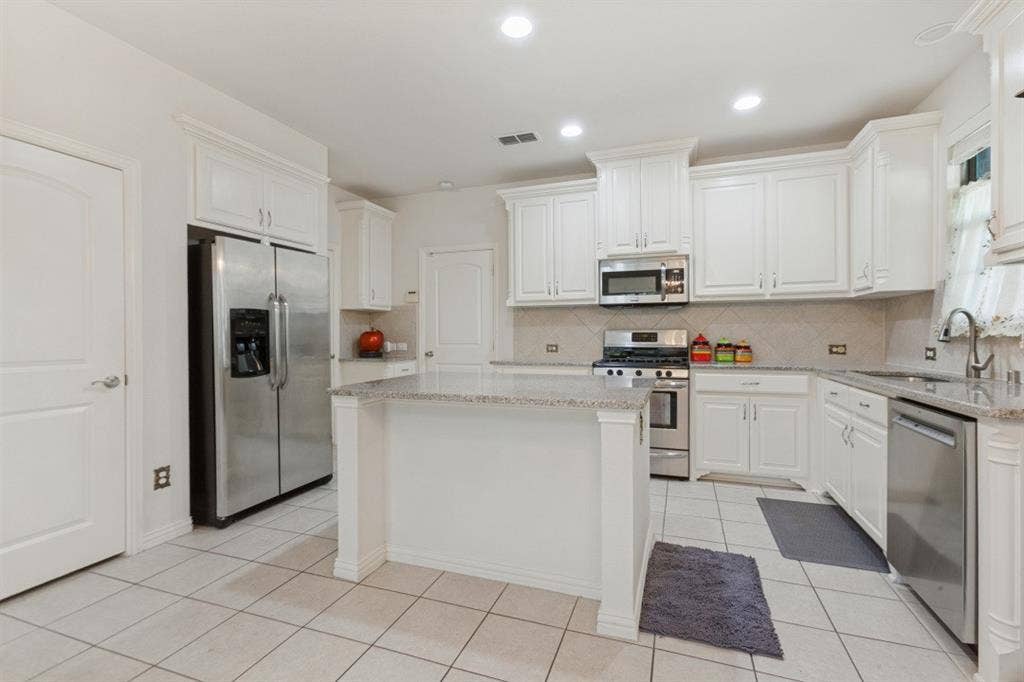 524 S Greenville Avenue, Richardson, TX 75081 Gourmet kitchen with white cabinetry, granite island, and stainless steel appliances.