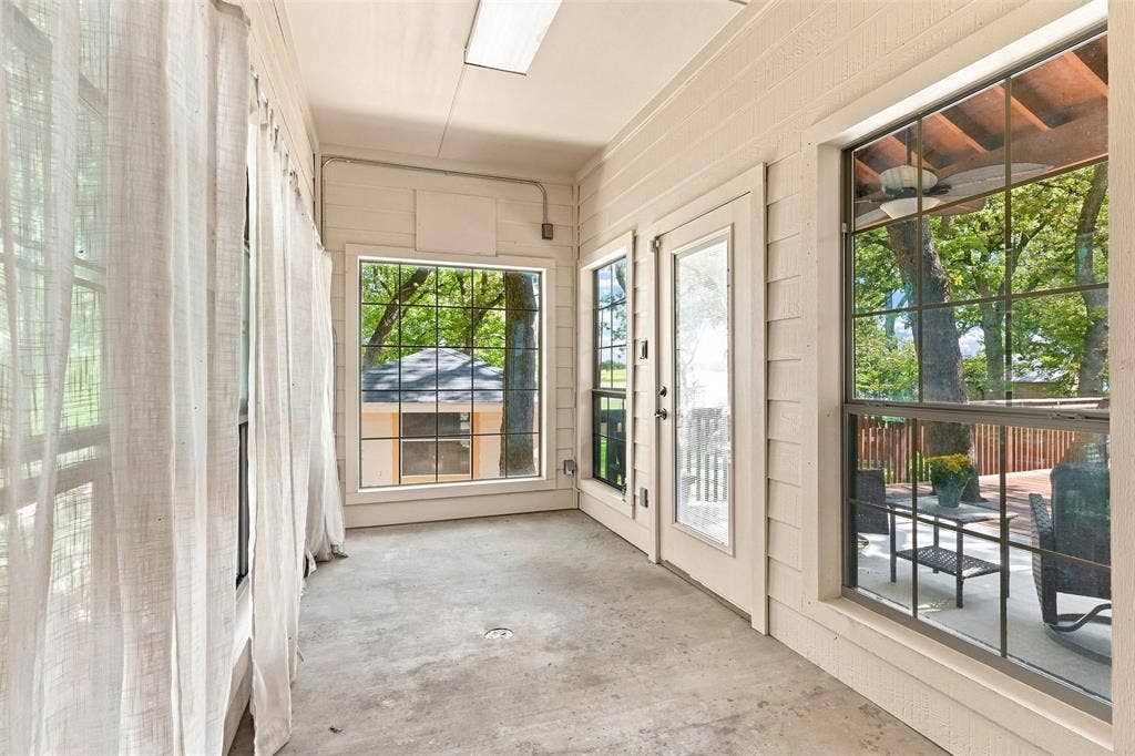 284 Shoreline Drive N, Azle, TX 76020 Enclosed porch featuring concrete flooring, multiple windows with grid patterns, and an exterior door with a glass panel