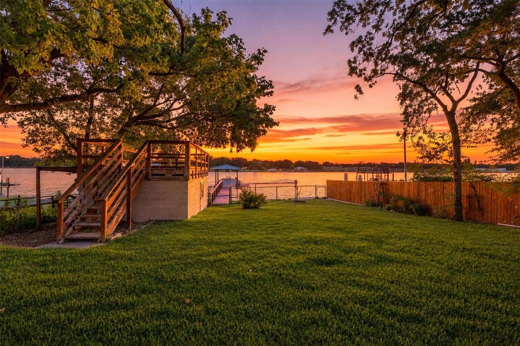 284 Shoreline Drive N, Azle, TX 76020 Expansive green lawn, multi-level wooden deck, private wooden dock, waterfront access, and mature trees