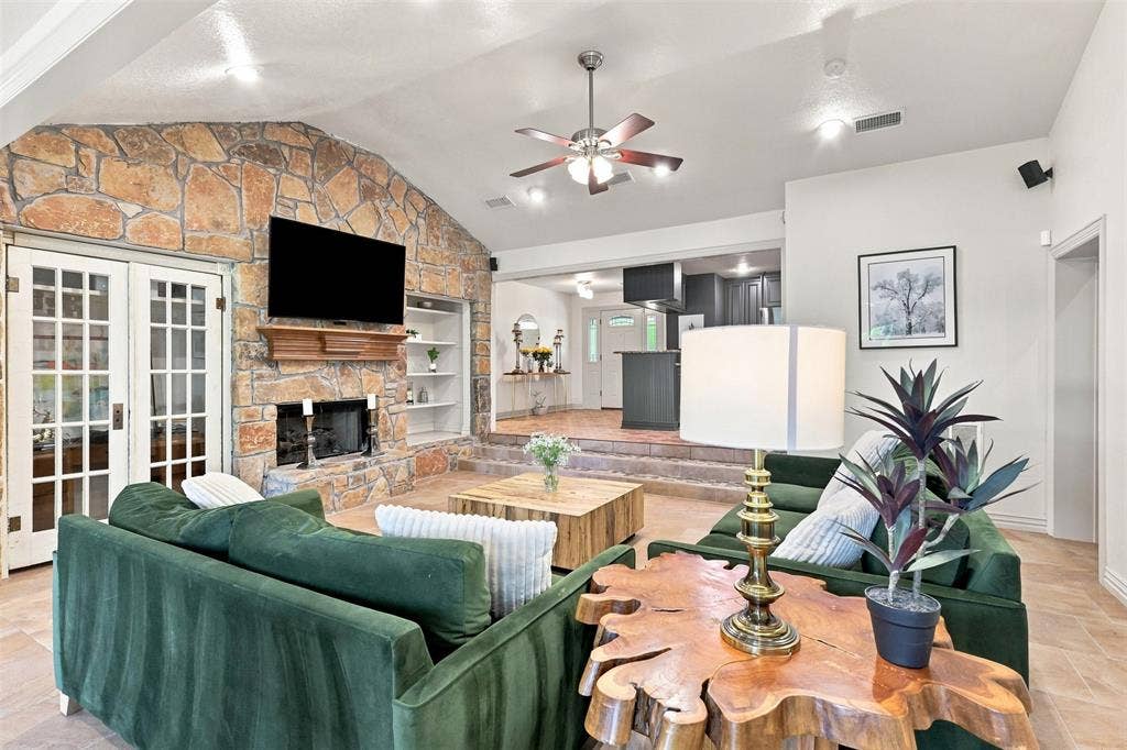 284 Shoreline Drive N, Azle, TX 76020 Vaulted ceiling featuring a ceiling fan, stone fireplace with a wood mantle, built-in shelving, and double French doors with glass panels