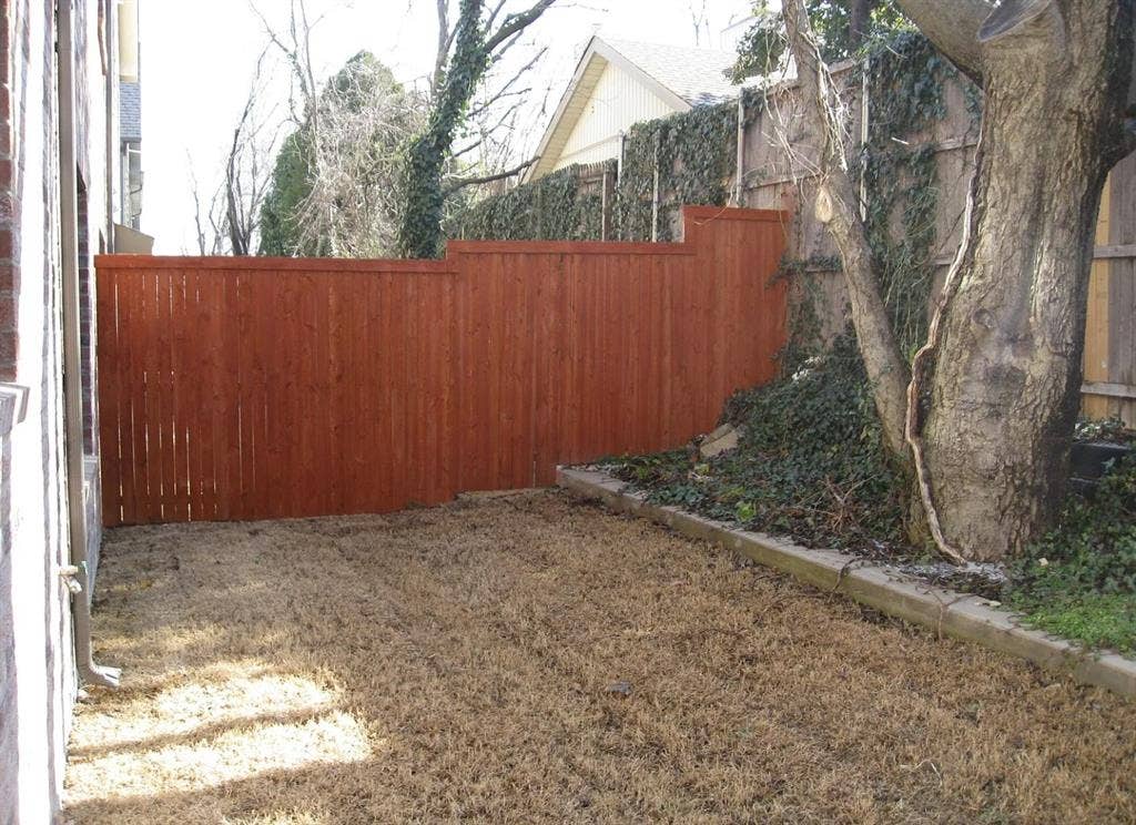 2514 Apollo Villa Road, Garland, TX 75044 Private backyard area featuring a wood fence, mature tree, and concrete curbing